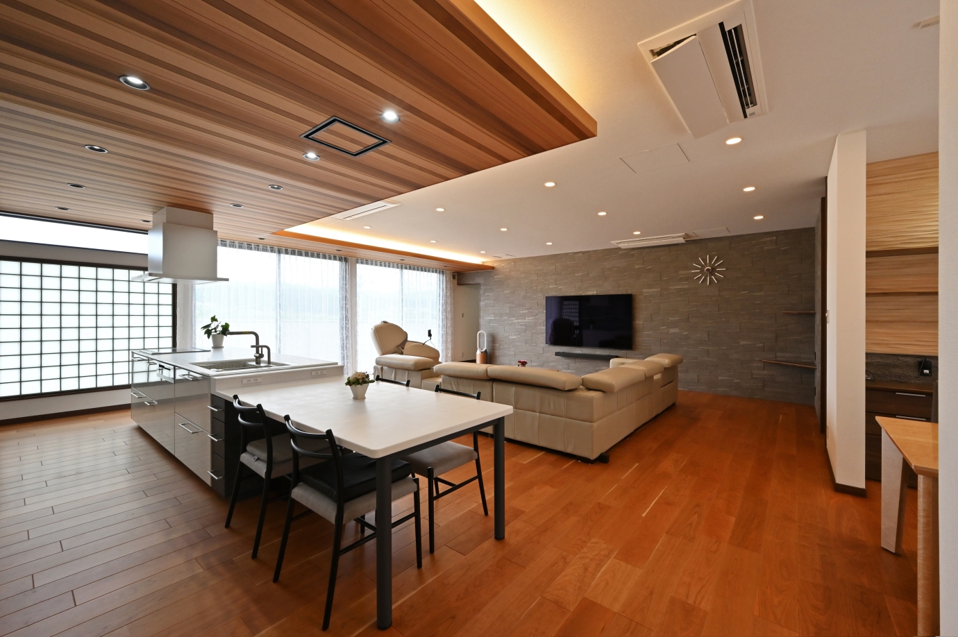 奈良の建築家が手がけた和モダン×ホテルライクな高級注文住宅のLDK空間。無垢フローリングと木天井、間接照明が美しいオープンキッチンとリビングが一体となったデザイナーズハウス。大開口の窓と障子が光をやわらかく取り込み、上質で快適な暮らしを実現する住まいの実例。