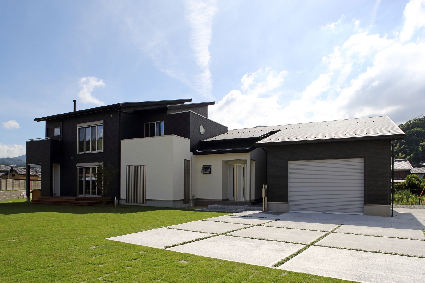 奈良県で建築家が設計したビルトインガレージ付きの和モダン注文住宅。黒と白の外壁が織りなす水平ラインの外観と、芝生の庭・中庭と連続する動線が、機能性と美しさを両立した住まい。